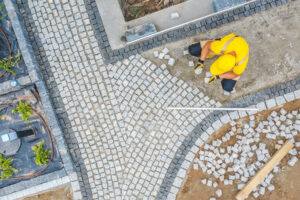 Caucasian Construction Worker in His 40s Paving Garden Path Aerial View. Garden Architecture Theme.