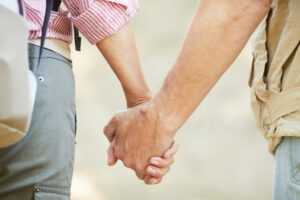 Close-up of mature couple holding hands and walking together outdoors in summer day